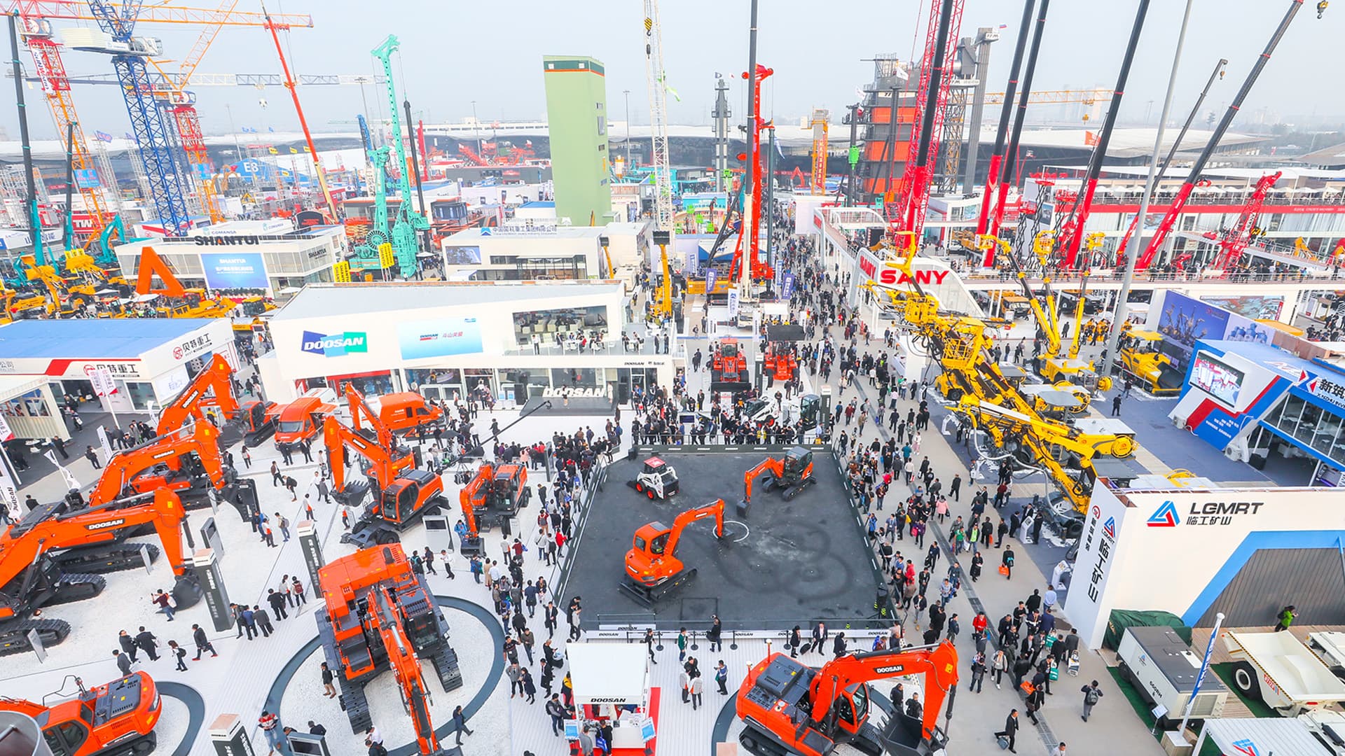 Aerial view of excavators, cranes, and crowds across the bauma China exhibition grounds, Shanghai